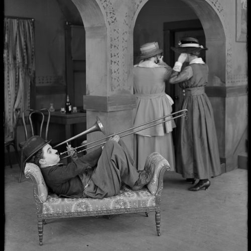 Chaplin s'essayant au trombone dans ses studios, 1918 © Roy Export Co Ltd